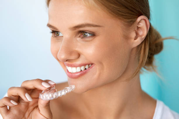 Smiling Woman With Beautiful Smile Using Teeth Whitening Tray Teeth Whitening. Beautiful Smiling Woman With White Smile, Straight Teeth Using Teeth Whitening Tray. Girl Holding Invisible Braces, Teeth Trainer. Dental Treatment Concept. High Resolution Image straight stock pictures, royalty-free photos & images