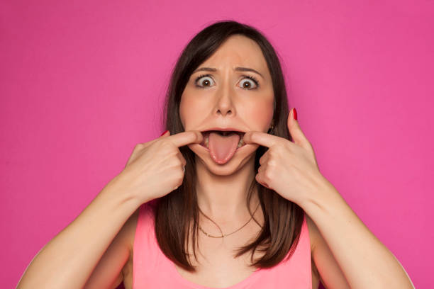 istock Young funny woman making silly faces on pink background 936821884