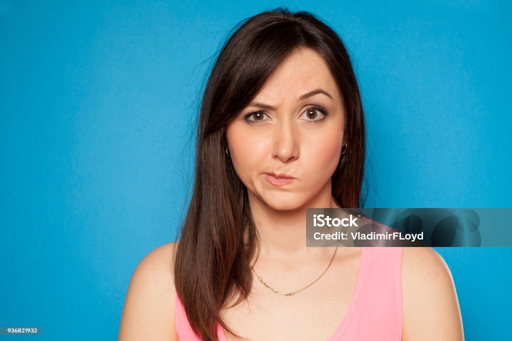 young woman looks suspiciously on a blue background Scolding Stock Photo