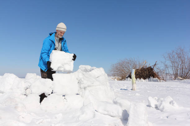 istock Man in a blue jacket building an igloo on a glade in the winter 936822216