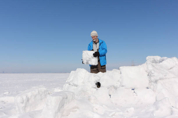 istock Man in a blue jacket building an igloo on a glade in the winter 936822224