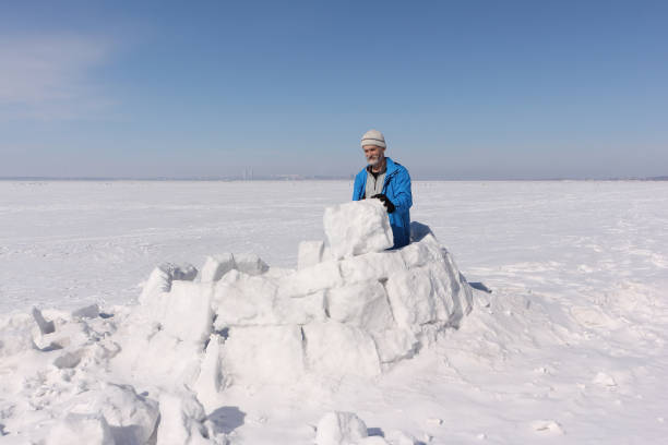 istock Man in a blue jacket building an igloo on a glade in the winter 936822264