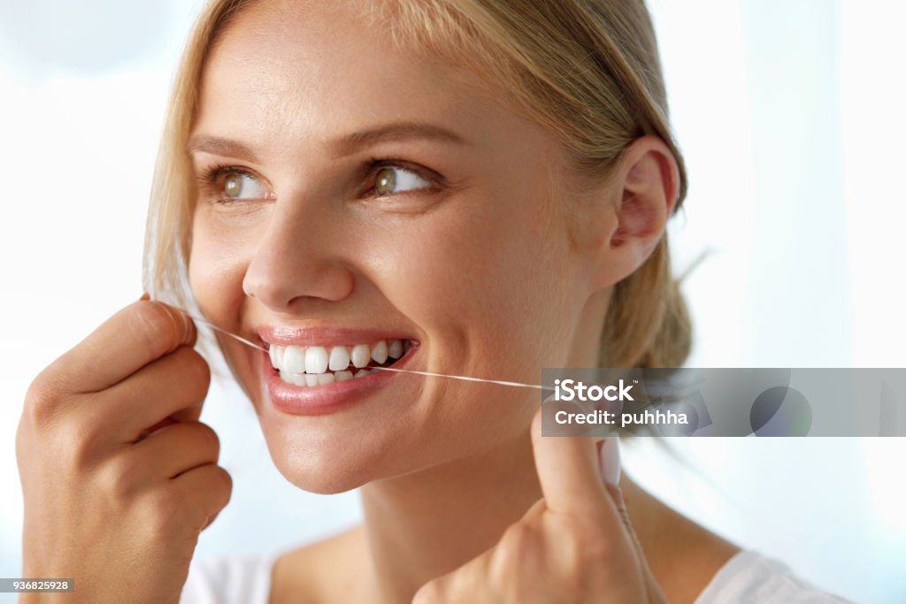 Zahnpflege. Wunderschöne lächelnde Frau Zahnseide gesunde weiße Zähne - Lizenzfrei Attraktive Frau Stock-Foto