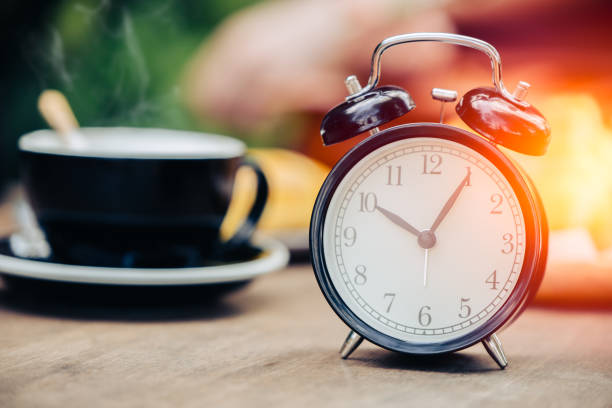 istock Coffee Times concept clock with coffee cup on wooden table 936840472