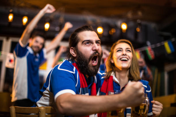 istock Happy couple celebrating while watching a football game in a bar 936842376