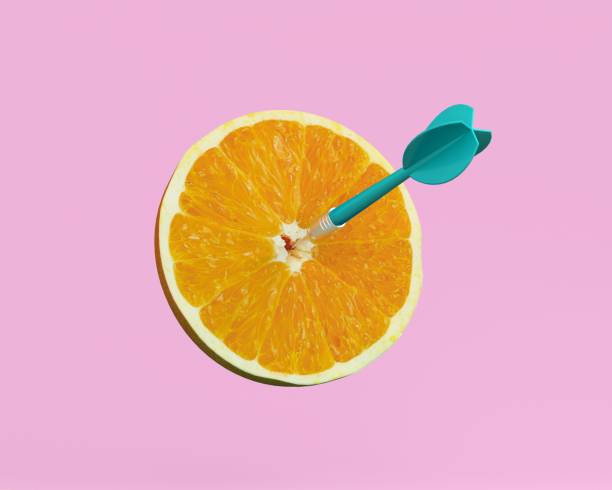 Orange slice, fruit with circular target marked and blue dart on pastel pink background. minimal idea food and fruit concept.Idea creative to produce work within an advertising marketing communication