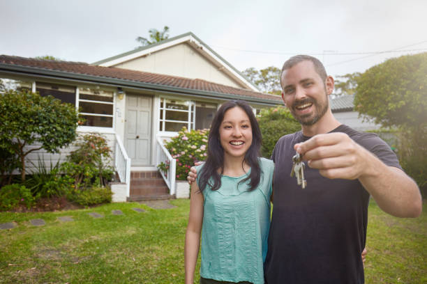 happy mixed-race couple showing the keys of the new house - garden key imagens e fotografias de stock