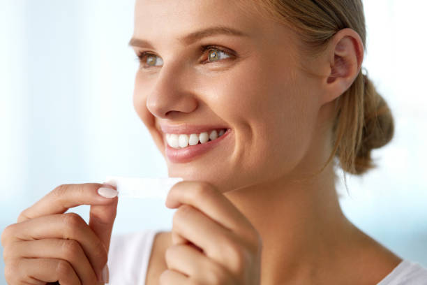 istock Woman With Healthy White Teeth Using Teeth Whitening Strip 936854780