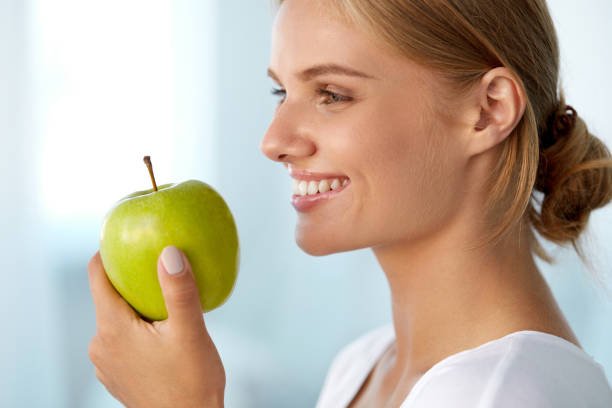 istock Beautiful Smiling Woman With White Teeth Eating Green Apple 936858632