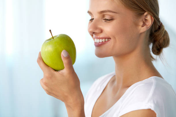 istock Beautiful Smiling Woman With White Teeth Eating Green Apple 936858872