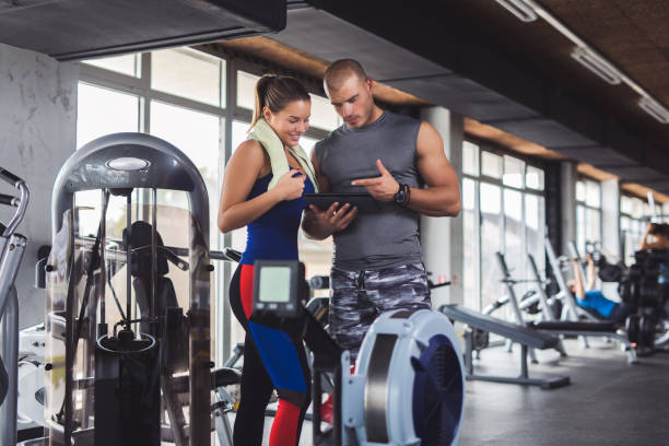 istock Young woman discussing workout progress with fitness instructor 936863472