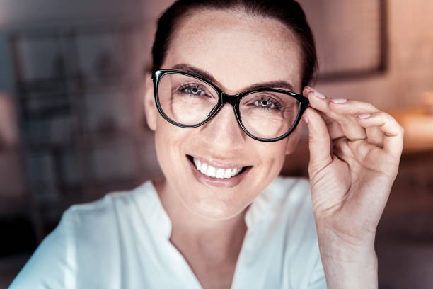 istock Satisfied pleasant woman supporting her glasses and smiling 936863896