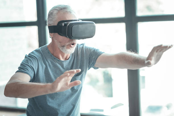 istock Impressed interested man holding hands up and tasting VR glasses 936877638