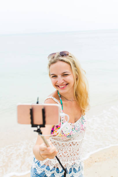 istock young, blond beautiful woman doing selfie photo with her smartphone on a great beach in thailand 936877708