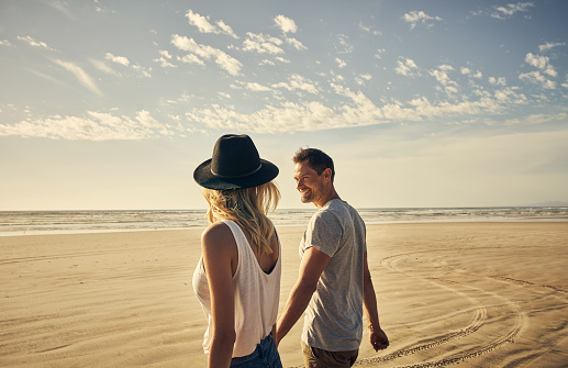 Shot of a young couple going for a romantic walk on the beach