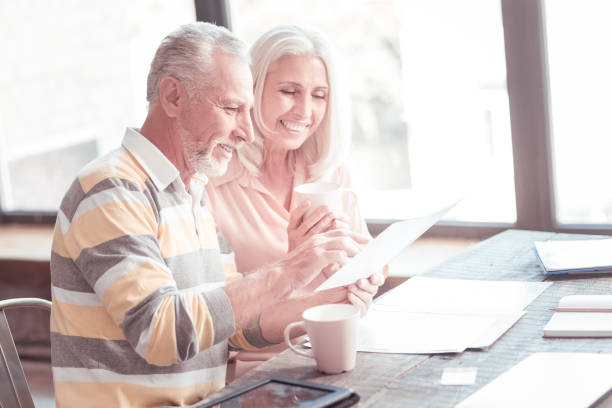 istock Satisfied aged man sitting and showing the document 936886872