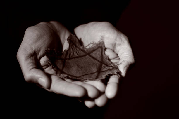 closeup of a ragged Jewish badge in the hands of a man, with a dramatic effect