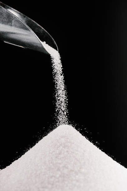 istock white sugar falling from metal scoop on pile isolated on black 936890340