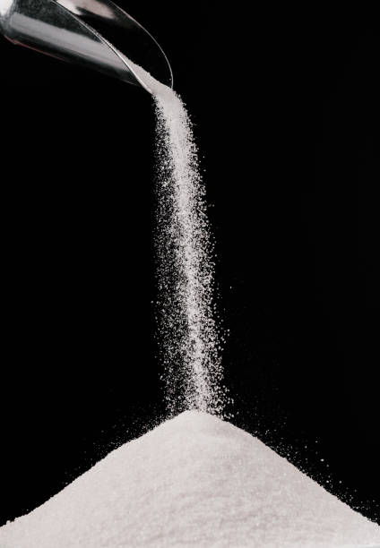 istock sugar falling from metal scoop on pile isolated on black 936890574