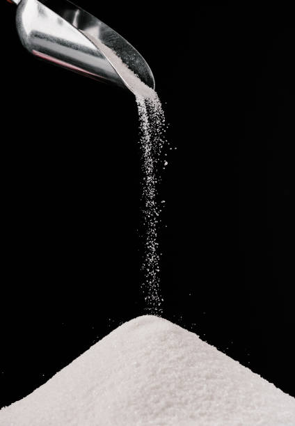 istock sugar falling from metal scoop on pile isolated on black 936890644