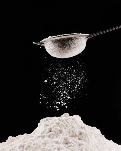 istock flour falling from sieve on pile for pastry isolated on black 936890772