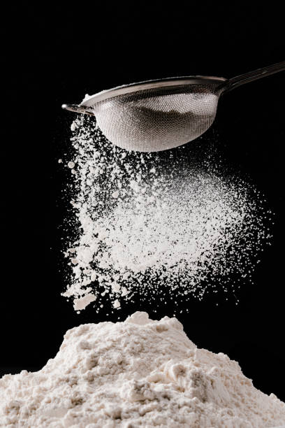 istock flour falling from sieve on pile isolated on black 936890824