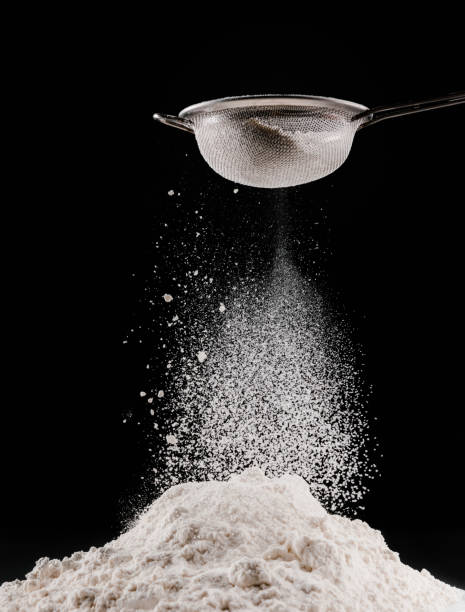 istock flour falling from sieve on pile isolated on black 936890950