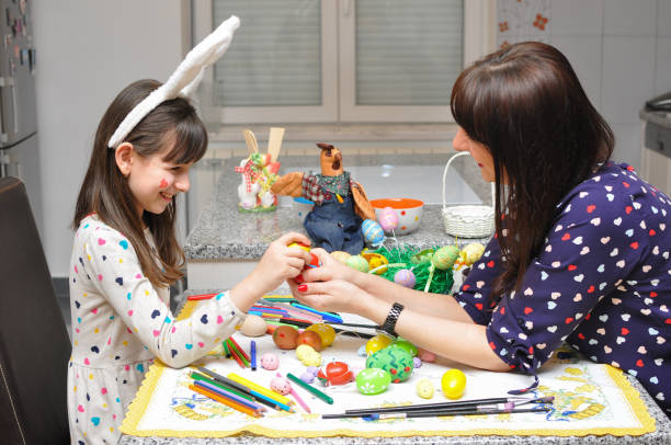 istock Mom and girl smiling and play with Easter eggs and paint 936893668