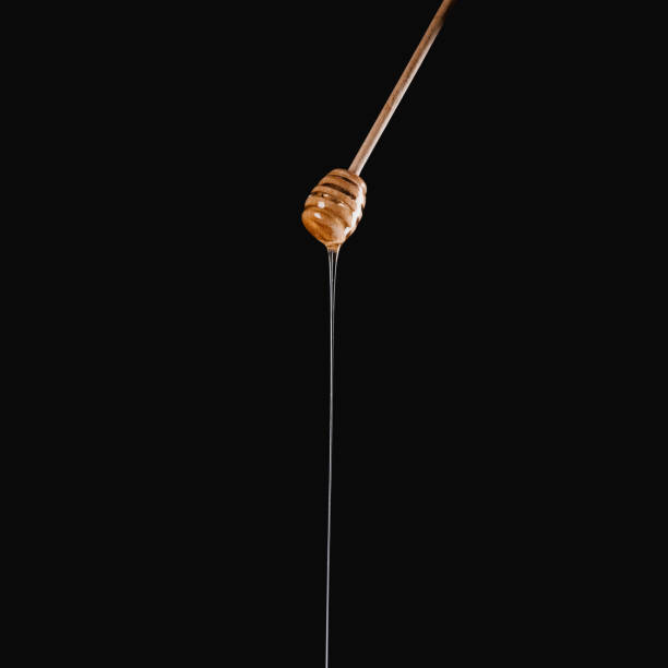 istock appetizing honey dripping from honey stick isolated on black 936894420