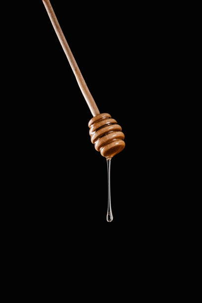 istock honey dripping from honey stick isolated on black 936894500