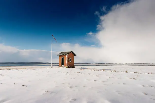 Winter landscape shot of the Shipping Pilot’s lookout post situated the island of Nyord in Denmark. The Pilot’s job was to guide ships around the treacherous waters that swirl around south Zealand and the small islands that make up the area between Nyord and Moen. Taken during a break in a snowstorm in March 2018. Colour, horizontal with some copy space.