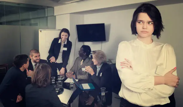 upset  woman in boardroom on background with working business colleagues