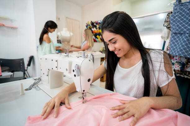istock Happy seamstress sewing on a machine at an atelier 936899228