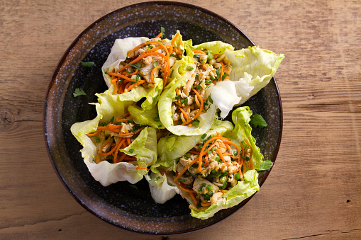 Lettuce wraps with chicken, carrot, peanuts and scallion. Stuffed iceberg lettuce leaves with chicken. View from above, top