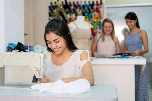 istock Happy seamstress sewing on a machine at an atelier 936901496