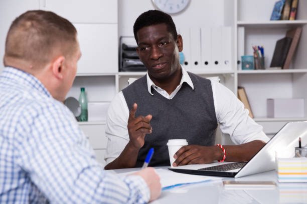 istock Serious male discussing with coworker in office 936902124