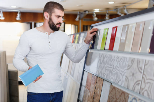 istock Positive man  holding sample of kitchen ceramic tile in modern store 936902724