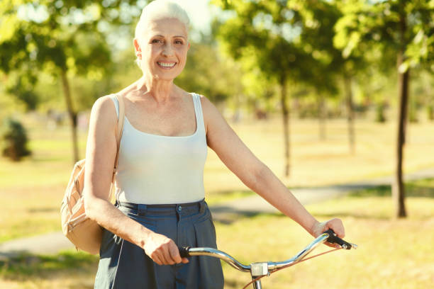 istock Joyful elderly woman holding bike handlebars 936907636