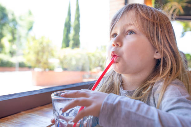 istock little child drinking water through red straw 936911432