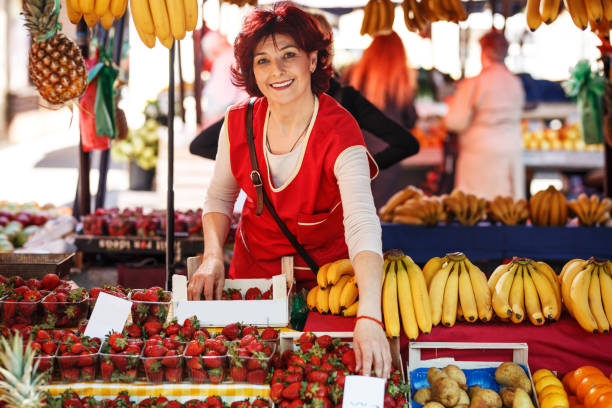 Mature age fruit market saleswoman selecting fresh fruit and preparing for working day. Mature age fruit market saleswoman selecting fresh fruit and preparing for working day. bazaar market photos stock pictures, royalty-free photos & images