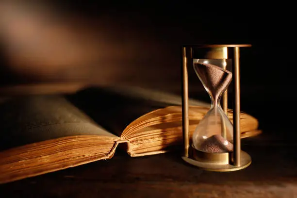 old hourglass and antique book with open pages