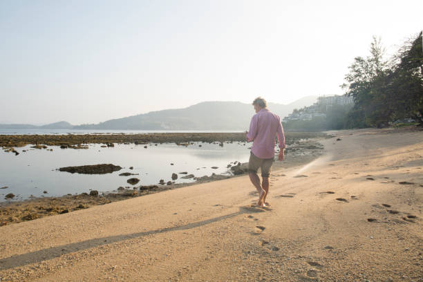 istock Man uses cell phone on tropical beach. 936916264