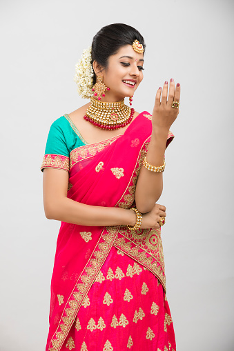 Beautiful Indian girl in traditional outfit with jewelry in studio shot.
