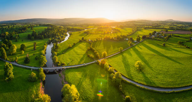 aerial panorama over idyllic countryside green fields mountains golden sunset - mountain valley river water imagens e fotografias de stock