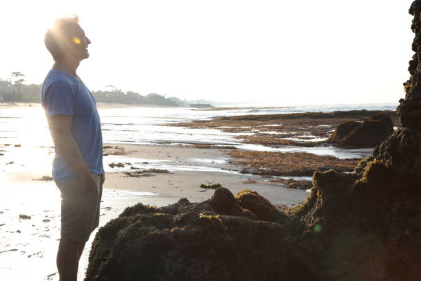 istock Man admires shrine on beach at sunrise 936924540