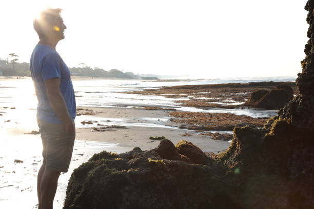 istock Man admires shrine on beach at sunrise 936924546