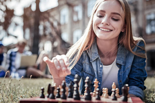 Happy young woman looking at the chess board