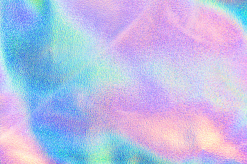 Holographic real texture in blue pink green colors with scratches and irregularities. Holographic color wrinkled foil. Holographic rainbow foil abstract background.