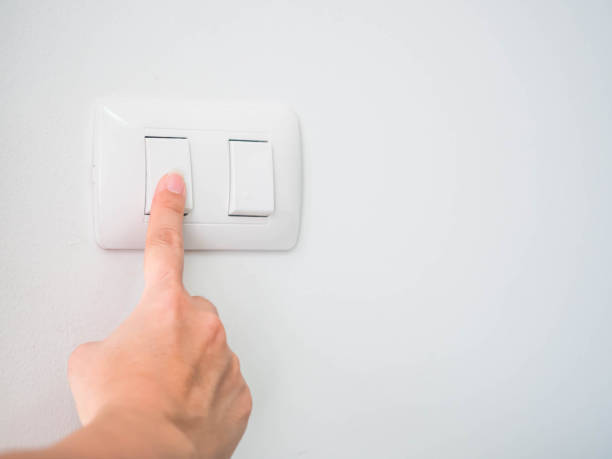 Woman is pressing the switch button for turning off the light. stock photo