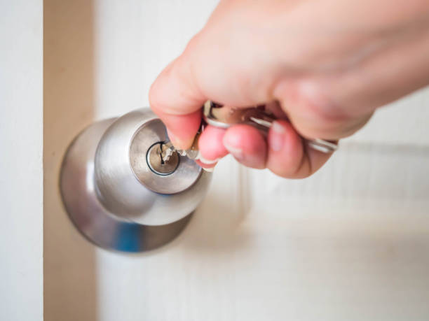 Woman insert the key into keyhole for unlocking the round door lock to open the door. stock photo